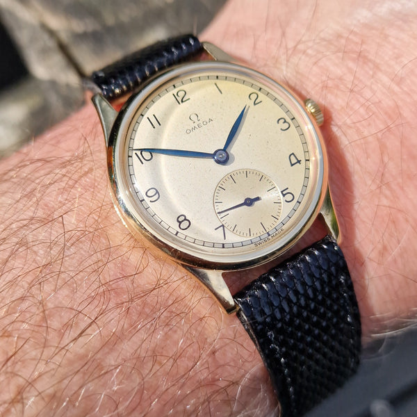 Vintage Omega watch on a person's wrist with a blurred background