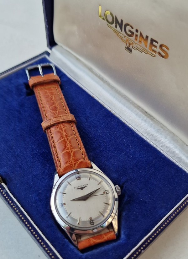 Longines watch with brown leather strap on a blue cushioned base