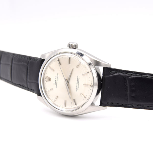 A vintage Rolex wristwatch with a silver-toned stainless steel case, cream-colored dial, and a black alligator leather strap, shown on a white background.