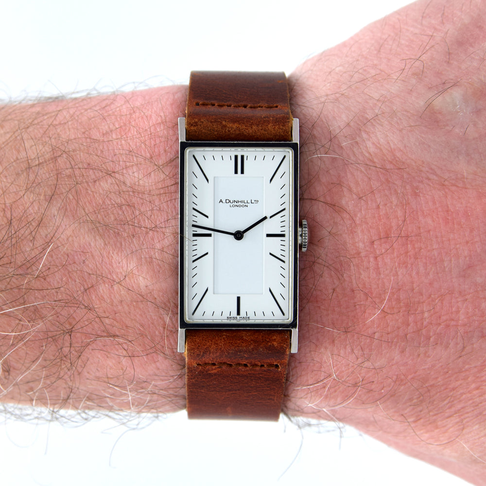 Watch with a brown leather strap on a wrist, brand 'A. Dunnill' visible