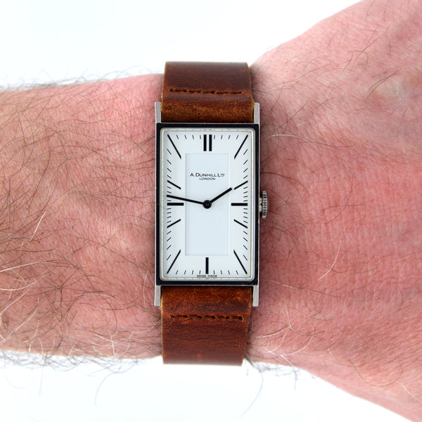 Watch with a brown leather strap on a wrist, brand 'A. Dunnill' visible