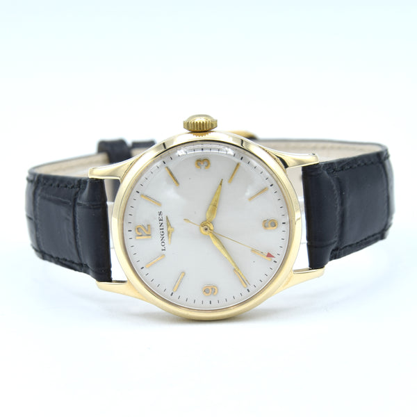 A vintage-style Longines wristwatch with a gold-tone case, white dial, and black leather strap, photographed on a clean white background.