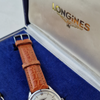 Longines watch with brown leather strap on a blue cushioned base