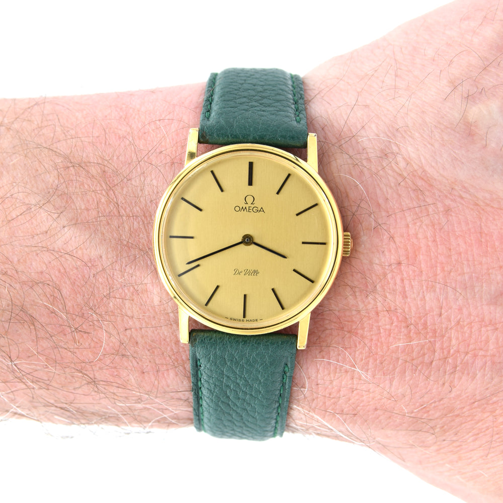 Gold watch with green strap on a wrist