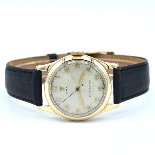 A vintage Rolex S watch with a gold-tone case, cream-colored dial, and a black leather strap, shown on a white background.
