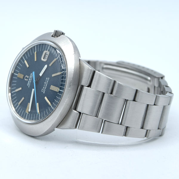Omega Seaweed stainless steel watch with a blue dial and silver metal bracelet, photographed on a light blue-white background.