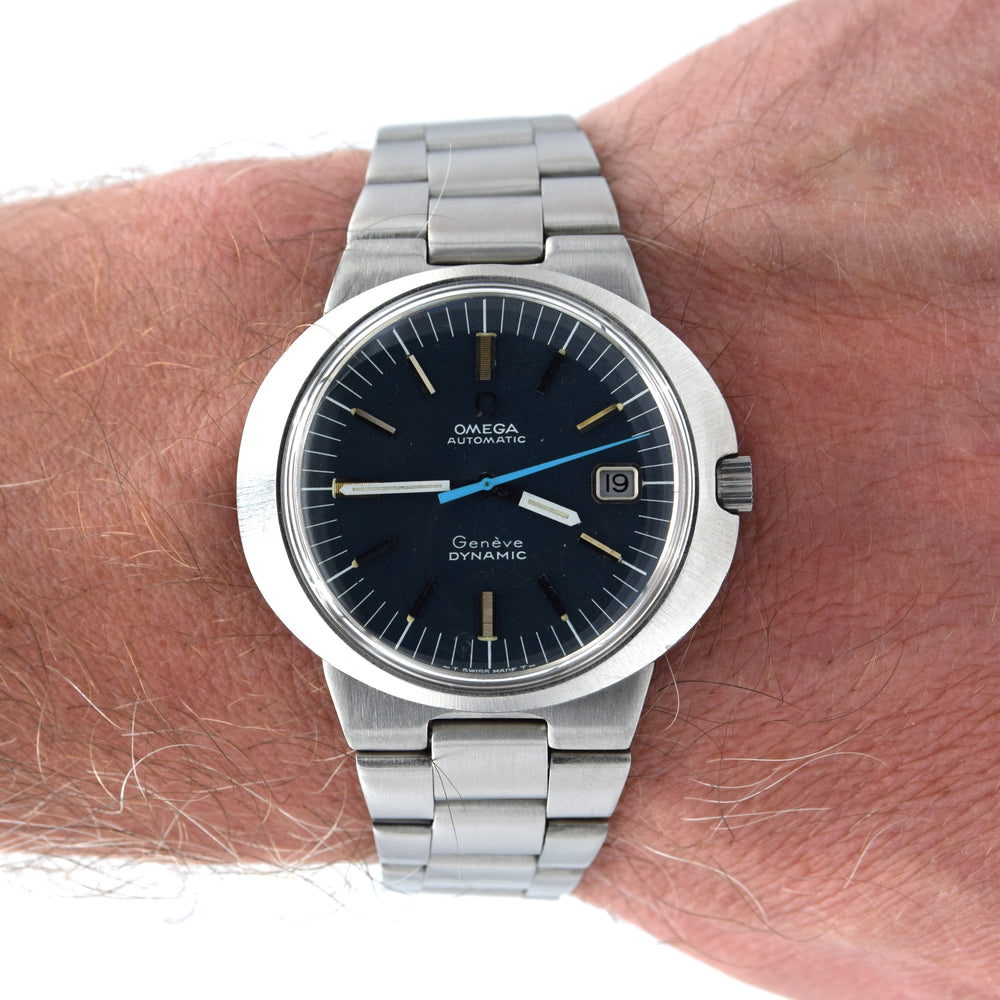 An Omega x A. Lange & Söhne Garden Dynamic wristwatch with a dark blue dial and silver stainless steel bracelet, shown worn on a person's wrist.