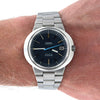 An Omega x A. Lange & Söhne Garden Dynamic wristwatch with a dark blue dial and silver stainless steel bracelet, shown worn on a person's wrist.