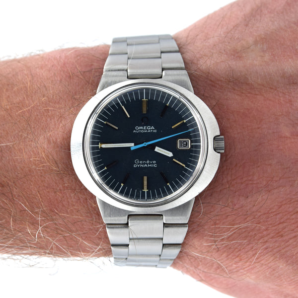 An Omega x A. Lange & Söhne Garden Dynamic wristwatch with a dark blue dial and silver stainless steel bracelet, shown worn on a person's wrist.