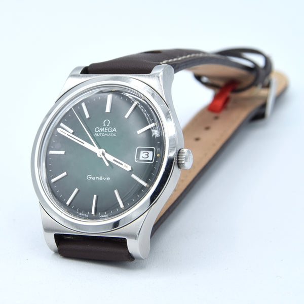 Omega Automatic wristwatch with a silver stainless steel case, dark gray dial, and brown leather strap, shown on a light gray background.