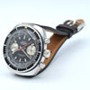 Swiss Emperor chronograph wristwatch with a silver stainless steel case, black bezel, dark gray dial, and a brown leather strap, photographed on a white background.