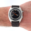 An Omega Cosmopolitan wristwatch with a black dial, silver-toned case, and black leather strap, shown worn on a person's wrist against a white background.
