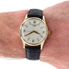 A Longines wristwatch with a gold case, white dial, and black leather strap, shown worn on a person's wrist against a white background.