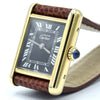 A Cartier watch with a gold-tone rectangular case, black dial with Roman numerals, and a brown textured leather strap, photographed on a white background.