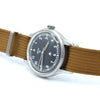 A vintage-style wristwatch with a black dial, silver-tone metal case, and a brown canvas strap, photographed on a clean white background.