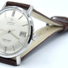 An Omega Swamaster automatic wristwatch with a silver-toned case, cream-colored dial, and a brown leather strap, photographed on a clean white background.
