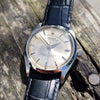 Vintage watch with a black leather strap on a wooden surface